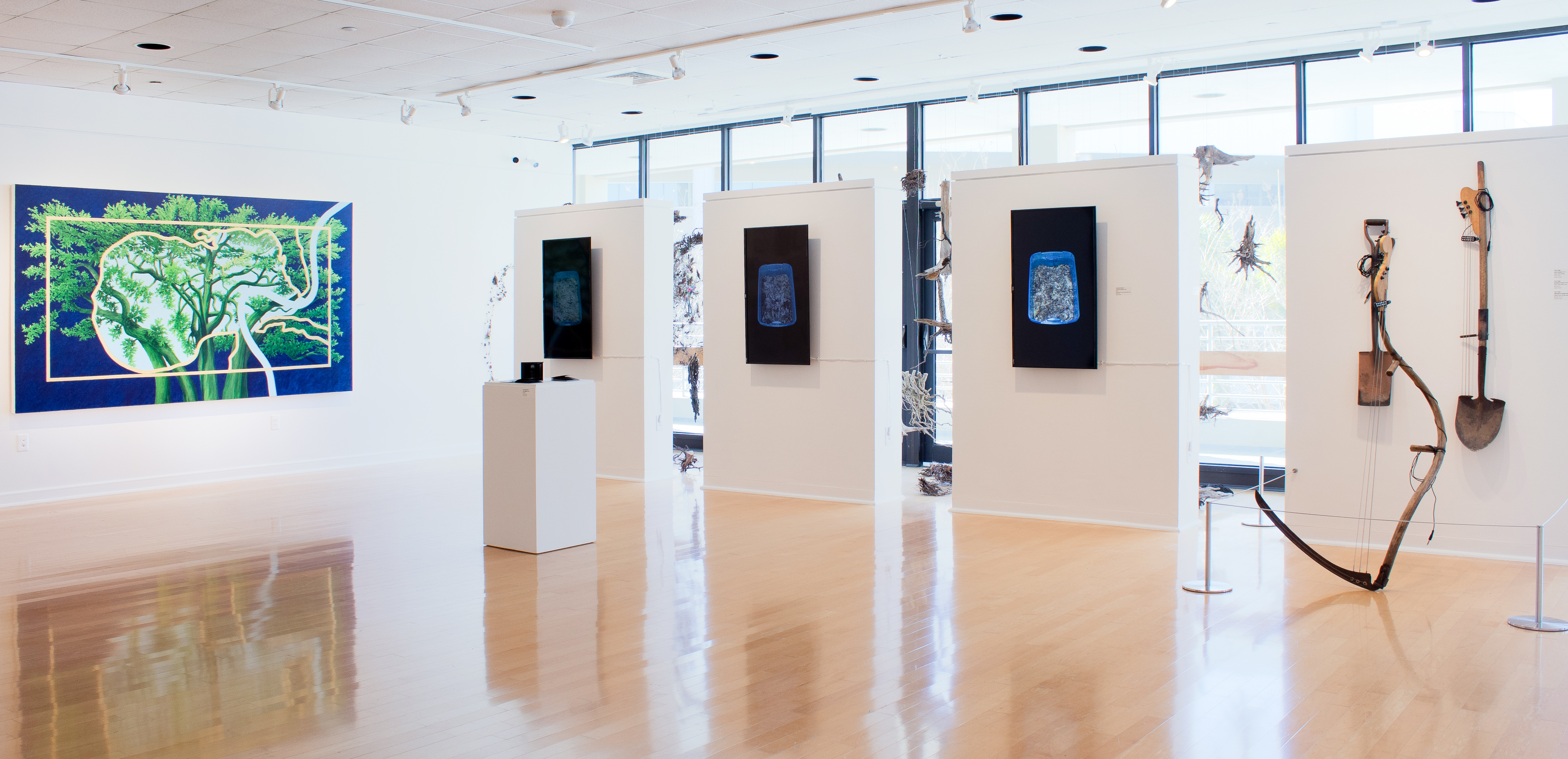 Wide shot of Gallery221 exhibition with paintings and sculptures.