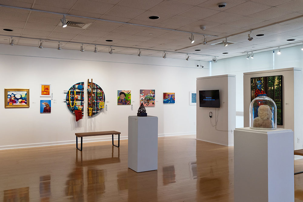 An art gallery with paintings, a mixed-media piece, and sculptures. A wooden bench sits below the artworks.