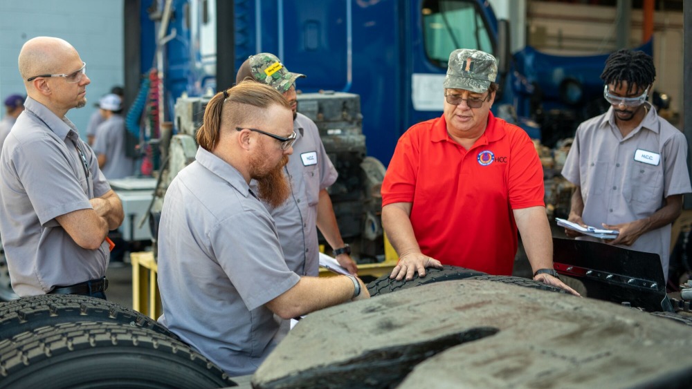 diesel tech faculty surrounded by students while he lectures them about truck tires.