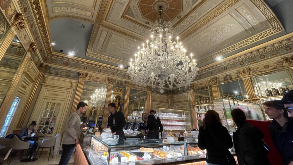 Some people in am ornately decorated room around a buffet