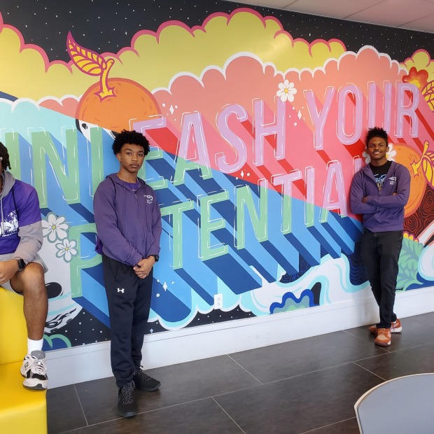 Three men in front of a mural