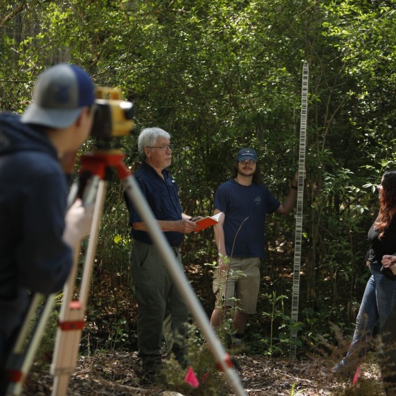 Surveyor in wooded area with three other people