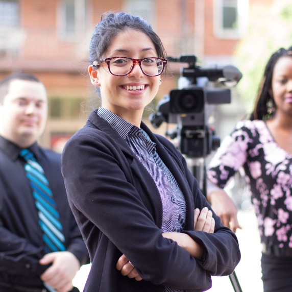 A diverse group of students outside of Ybor City next to a camcorder on a tripod