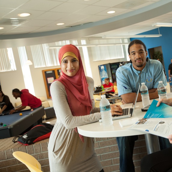 students sitting at a table smiling at the camera