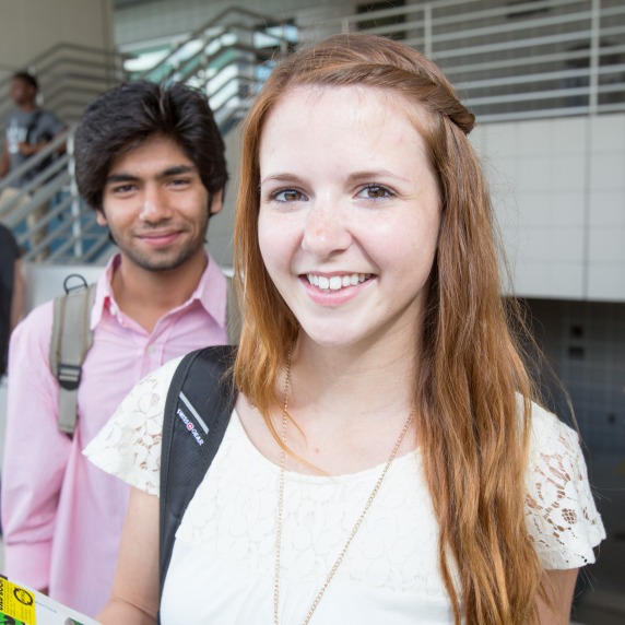 Two students standing smiling with backpacks.