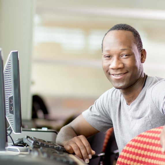 student sitting in computer lab smiling at camera