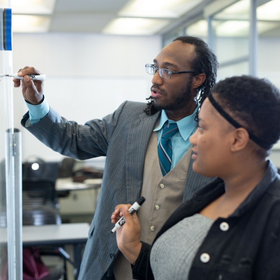 Two people writing on whiteboard