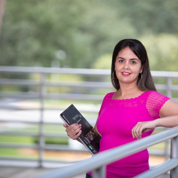 Student standing holding book.