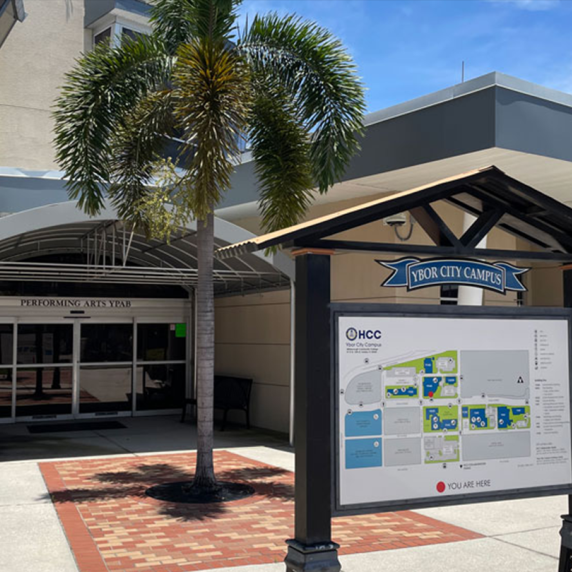 Entrance to a building at Ybor City Campus with a campus map and a palm tree.