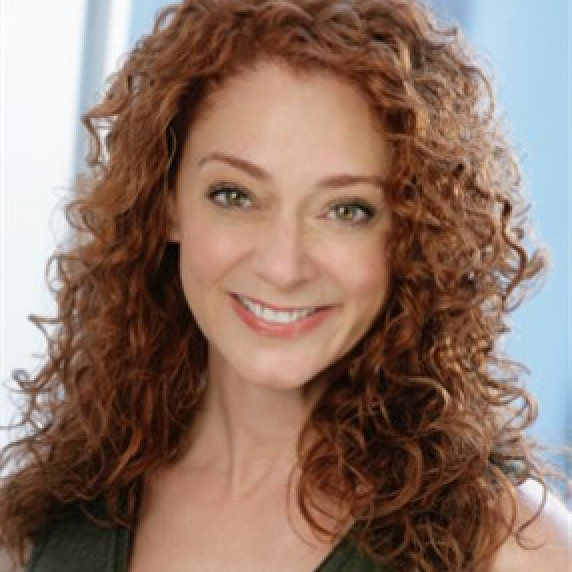 A woman with long red hair smiles at the camera.