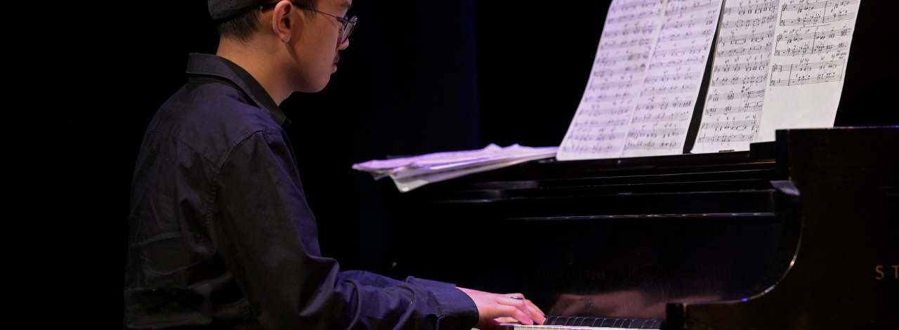 Person playing piano with sheet music