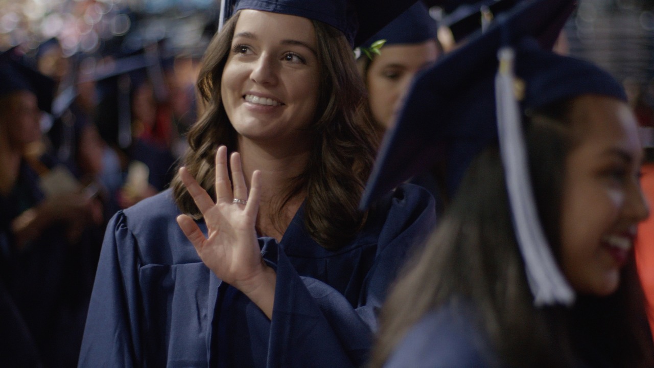 Graduate at commencement waving