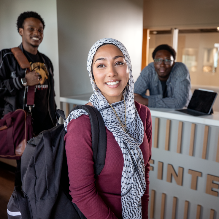 Students smiling at the camera inside a Fintech classroom. 