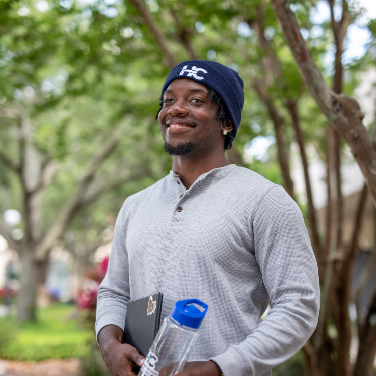 Male student smiling while standing outside. 