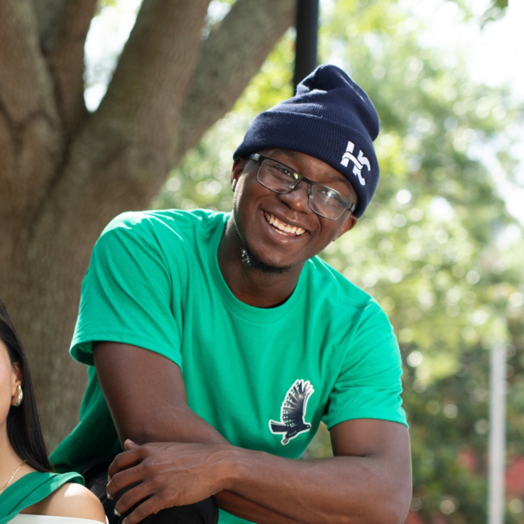 Male student wearing HC branded beanie and shirt smiling at the camera.